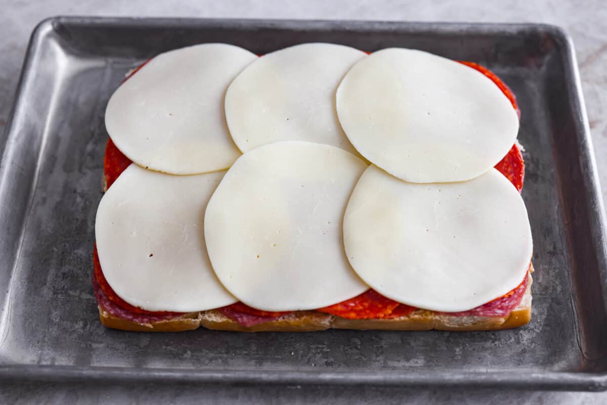 The classic grinder sandwich made into sliders to share! You've got Hawaiian rolls topped with layers of pepperoni, salami, turkey, provolone, and creamy grinder salad. And to top things off- each roll is brushed with a buttery parmesan glaze and baked to golden brown perfection. Next layering the cheese onto the sliders
