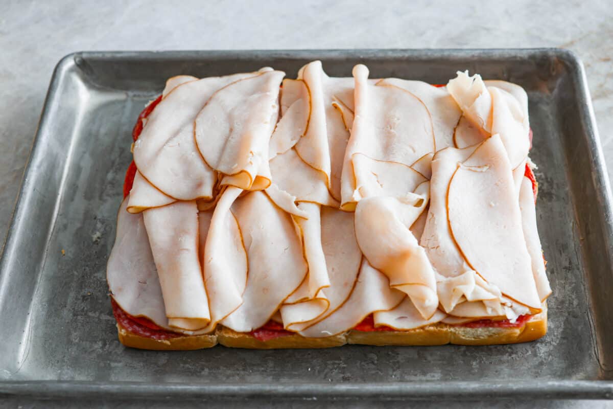 The classic grinder sandwich made into sliders to share! You've got Hawaiian rolls topped with layers of pepperoni, salami, turkey, provolone, and creamy grinder salad. And to top things off- each roll is brushed with a buttery parmesan glaze and baked to golden brown perfection. Layering turkey on top of the cheese
