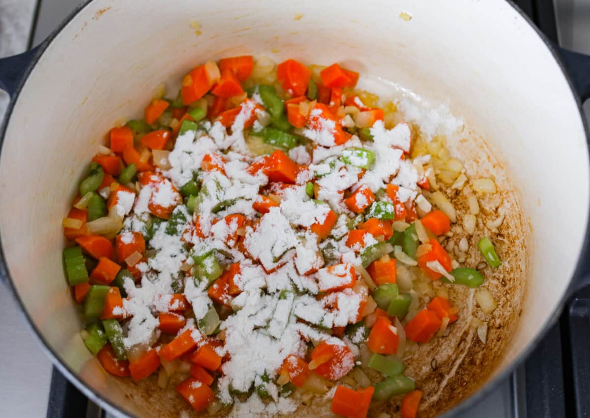Comforting ham and bean soup is a classic and hearty soup. It's loaded with creamy white beans, smoky ham, and tender veggies. It's the perfect soup for using up your leftover ham and super easy to make on those busy weeknights. Second process photo of the flour sprinkled over the veggies.