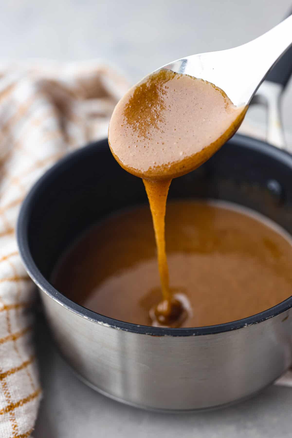 Elevate your Easter ham with this super easy homemade glaze! Made with simple spices, brown sugar, honey, and butter, itโs the best way to add extra flavor and texture. A must-make! The glaze dripping off a metal spoon.