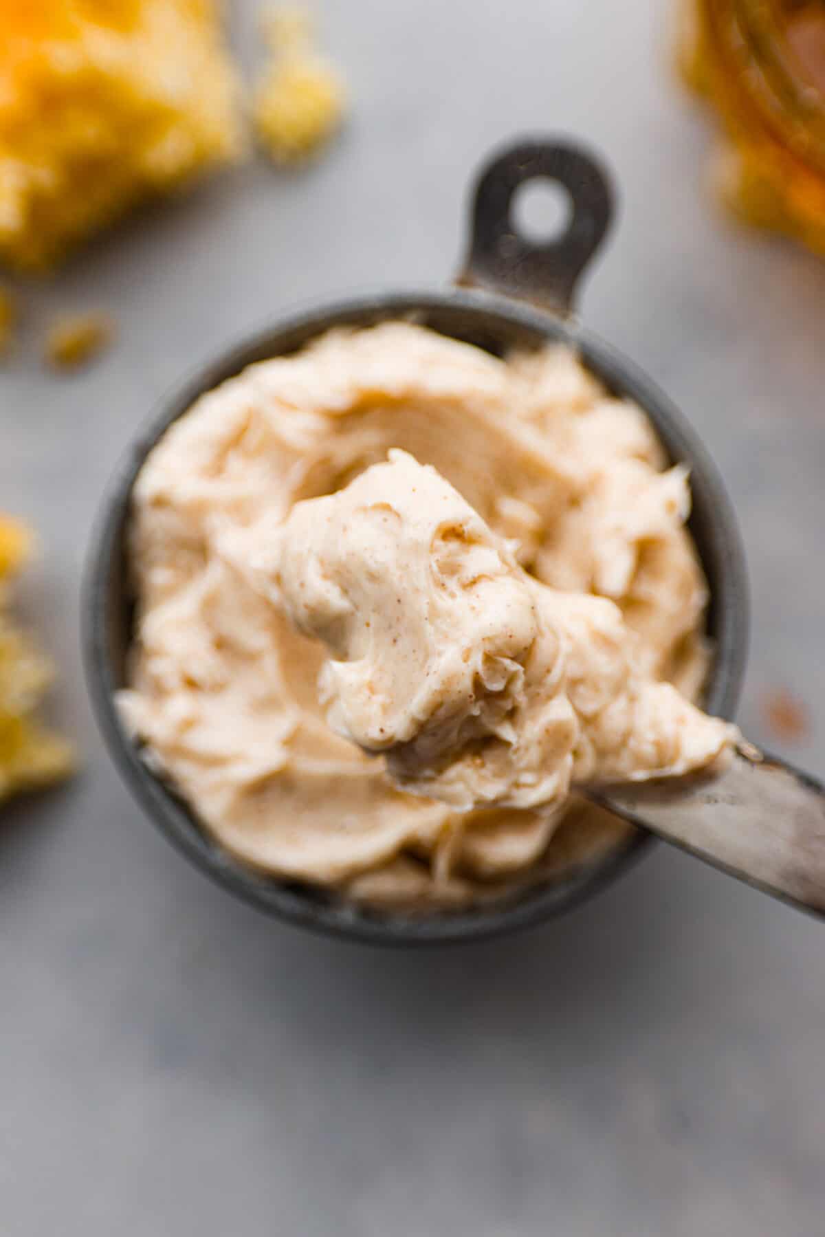 This honey butter recipe is so easy to make, and perfect on everything from rolls and toast to muffins. One taste and you’ll be hooked! Closeup of a small bowl filled with honey butter, and a butter knife covered in it.