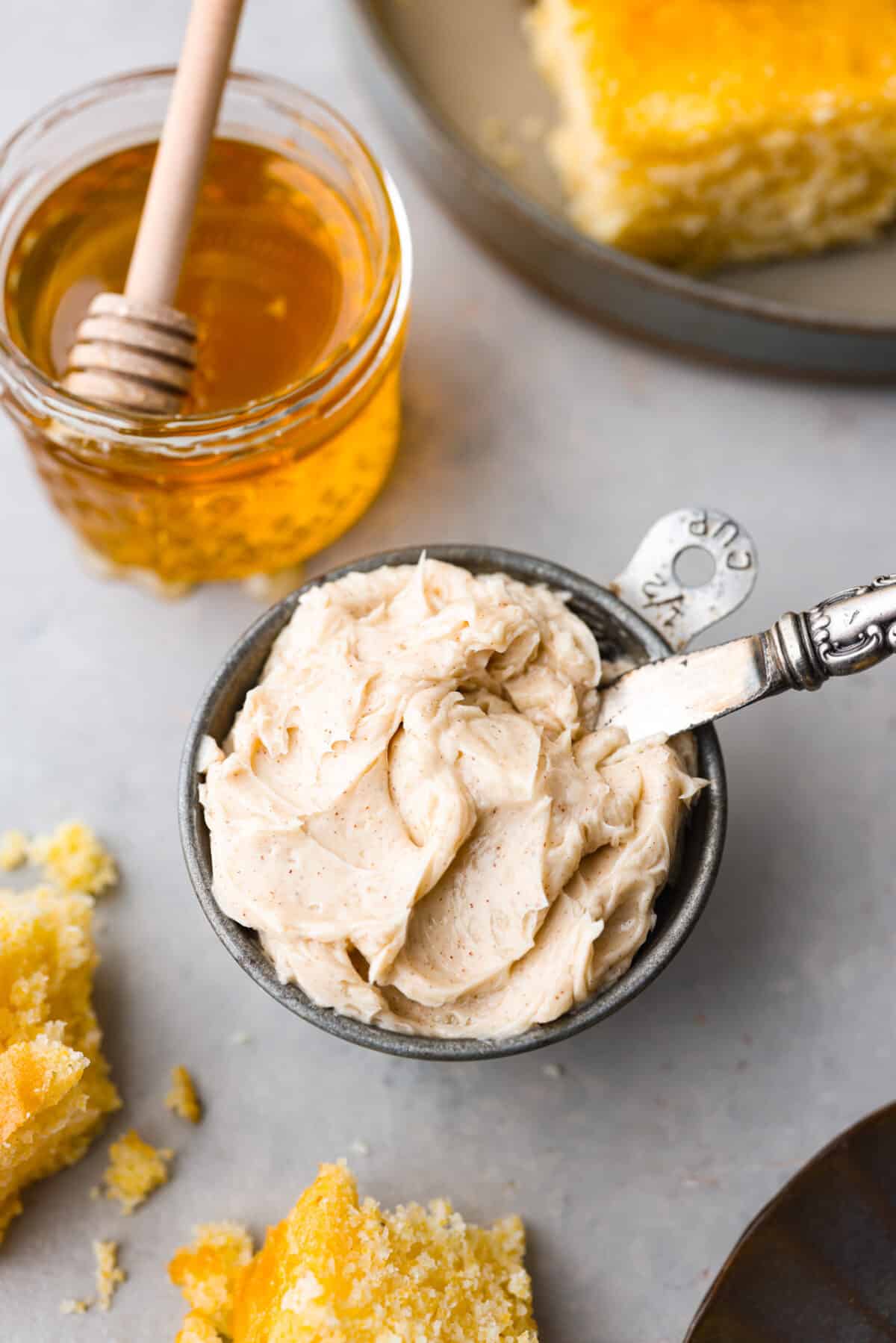 This honey butter recipe is so easy to make, and perfect on everything from rolls and toast to muffins. One taste and you’ll be hooked! A small bowl of honey butter next to a jar of honey.