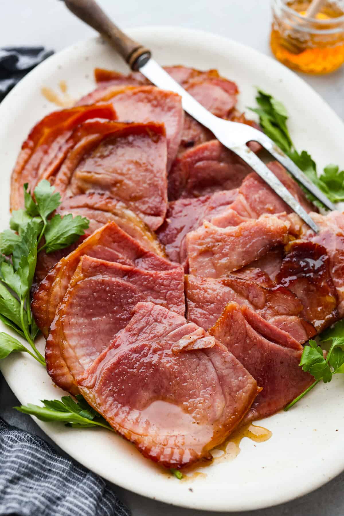 This honey-glazed ham is coated with delicious brown sugar and sweet honey glaze! It’s tender and juicy and goes with everything which makes it ideal for any holiday meal! A honey glazed ham, cut into slices.