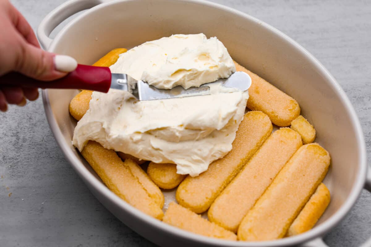 Meet lemon tiramisu! The most amazing citrusy twist on a classic Italian dessert. The layers of mascarpone cream and lemon curd will have you reaching for another slice! Layering the ladyfingers and mascarpone cream.