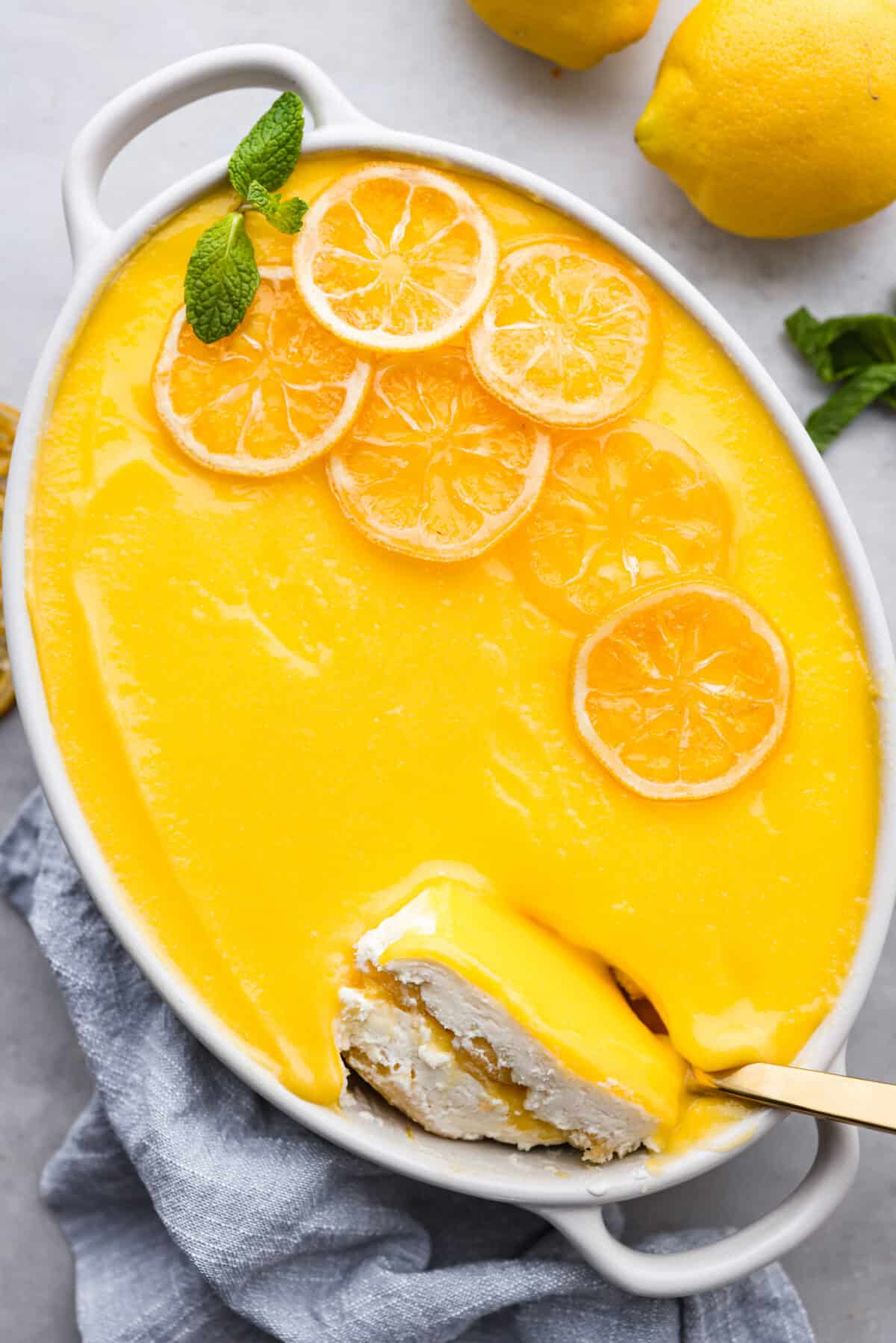 Meet lemon tiramisu! The most amazing citrusy twist on a classic Italian dessert. The layers of mascarpone cream and lemon curd will have you reaching for another slice! Lemon tiramisu in a white baking dish.