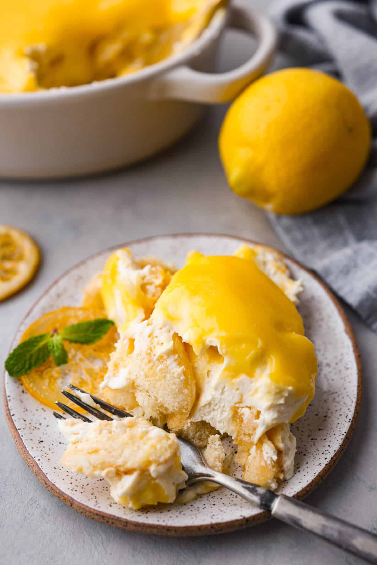 Meet lemon tiramisu! The most amazing citrusy twist on a classic Italian dessert. The layers of mascarpone cream and lemon curd will have you reaching for another slice! A serving of the tiramisu on a small plate.