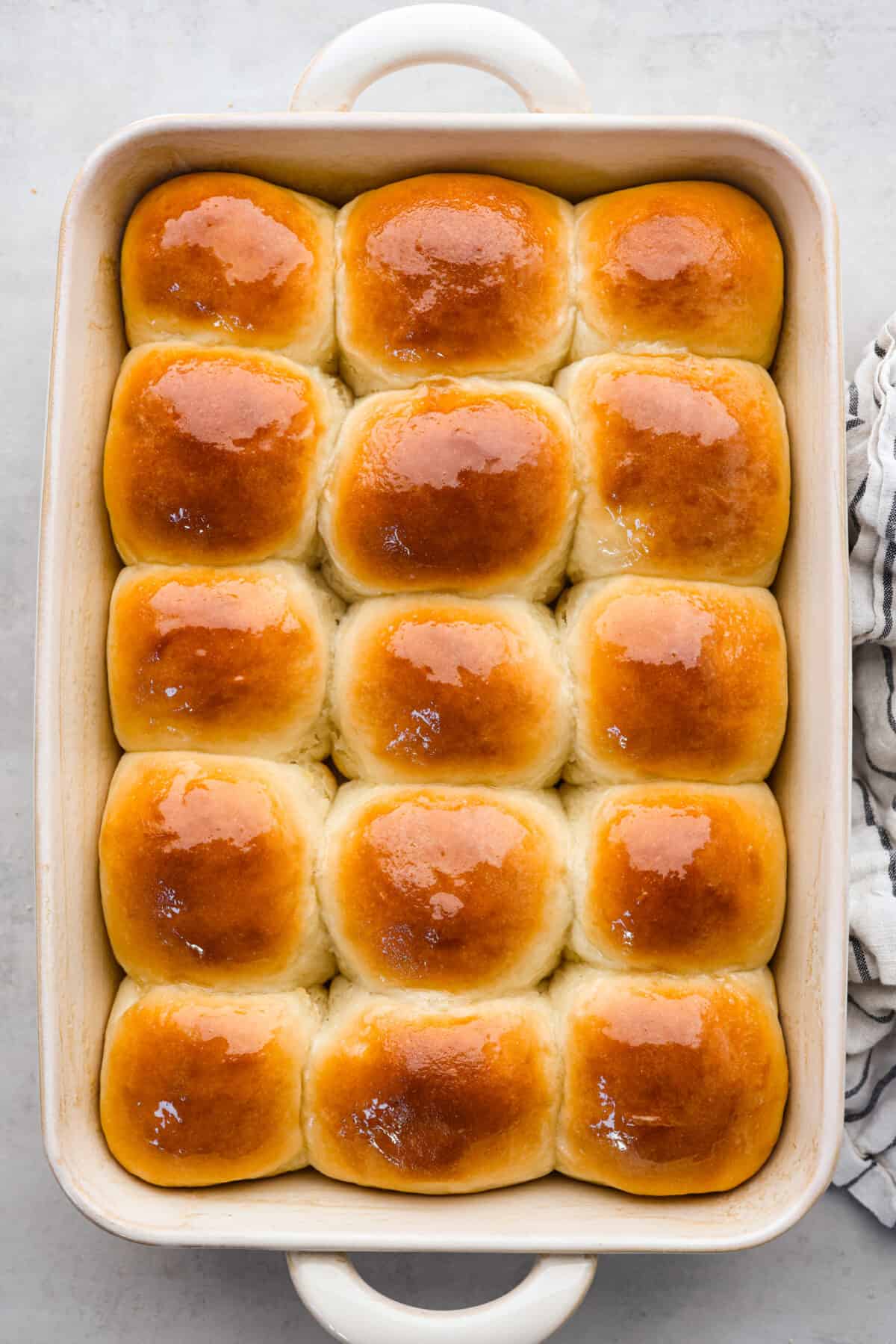 Perfectly soft buttery rolls will be your classic go-to roll recipe! They are tender fluffy, and baked with a buttery golden top. These rolls are sure to be a family favorite! Top view of perfect soft and buttery rolls baked in a baking dish.