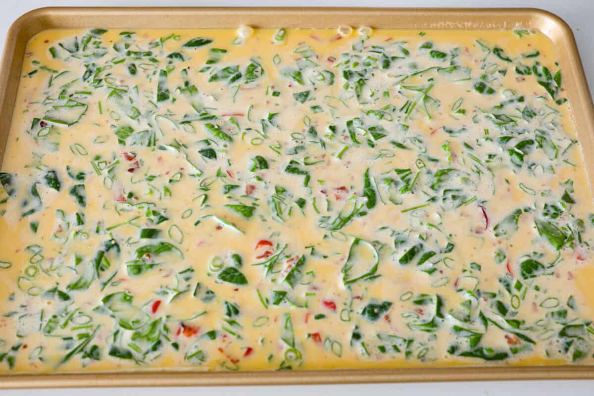Sheet pan eggs are not only fluffy and full of flavor, but the best way to meal prep eggs or feed a crowd! Add your favorite mix-ins and serve as-is or use them to make breakfast sandwiches or as a topping for avocado toast! Pouring the whisked egg mixture into the sheet pan.