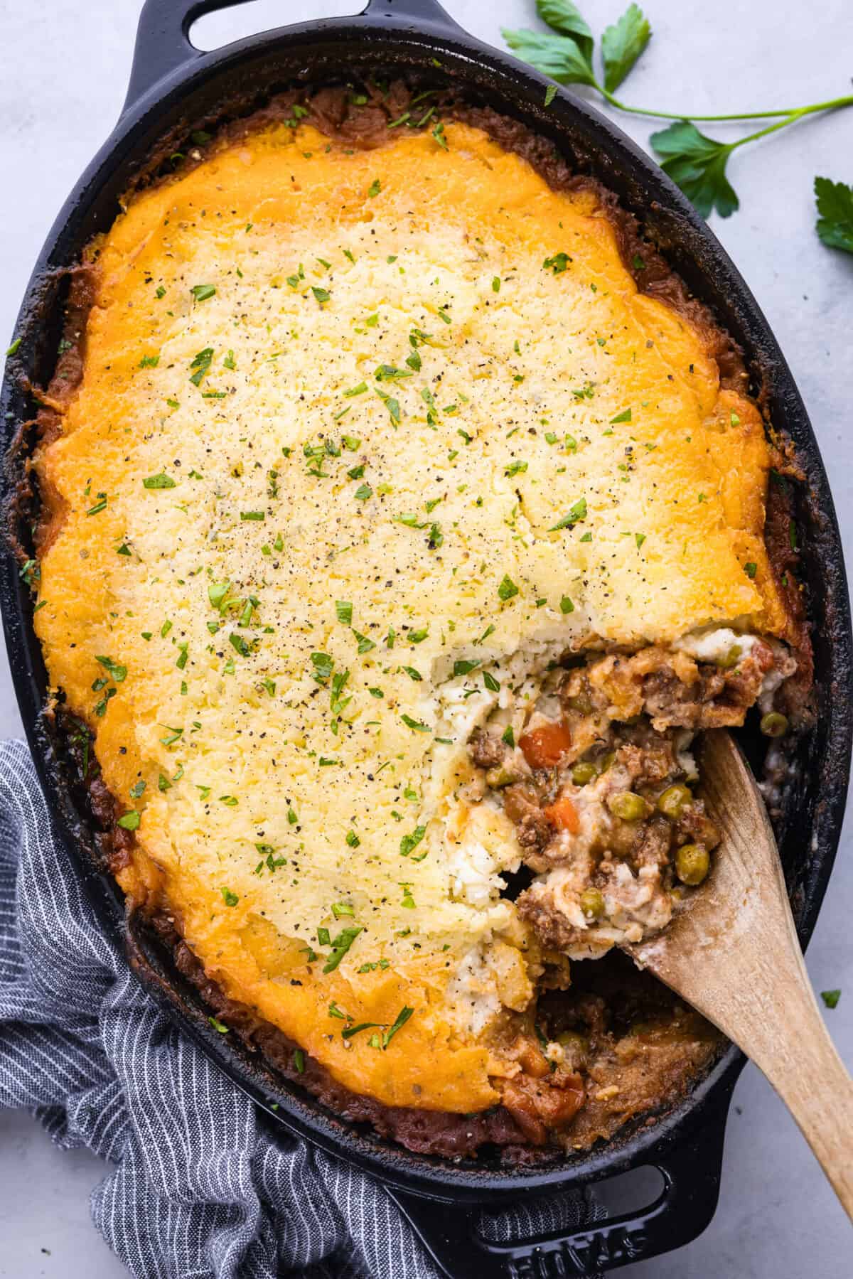 This easy Shepherd's Pie recipe is made with a saucy ground beef base, vegetables and creamy mashed potatoes. It's a hearty make-ahead meal for busy weeknights or Sunday dinner! Top-down view of shepherd's pie in a baking dish with a scoop taken out of it.