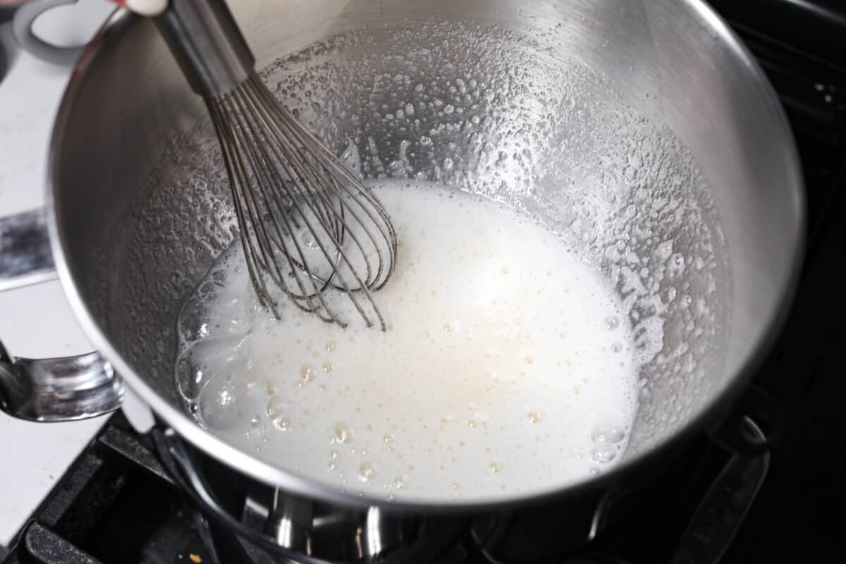 The most delicious Swiss Meringue Buttercream is easy to make with just 5 simple ingredients! It whips up deliciously light and silky with the right amount of sweetness. The perfect finishing touch for all of your favorite treats! Whisking the egg whites and sugar together.