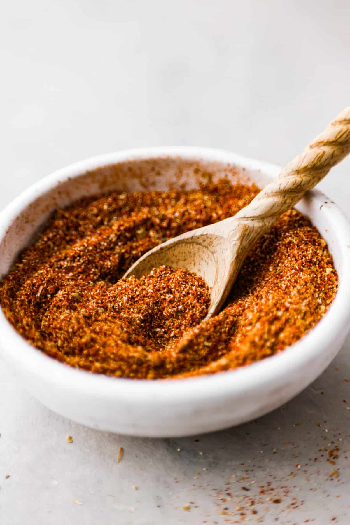 This Homemade Taco Seasoning is so flavorful and takes less than 5 minutes to make. You will never buy taco seasoning from the store again! A white bowl of taco seasoning with a wooden spoon.