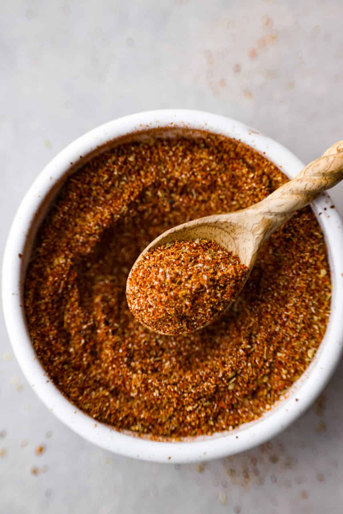This Homemade Taco Seasoning is so flavorful and takes less than 5 minutes to make. You will never buy taco seasoning from the store again! The top view of taco seasoning in a bowl with a wooden spoon scooping out some seasoning.