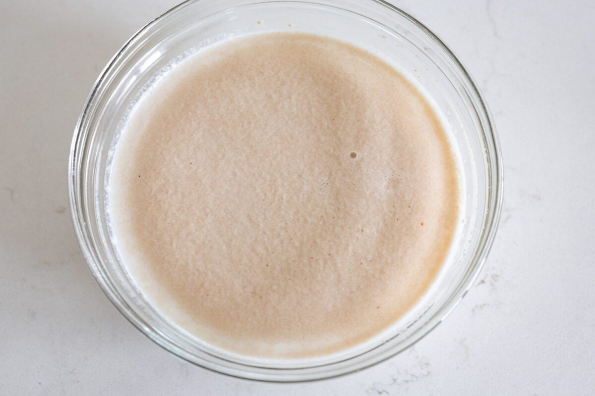 Perfectly soft buttery rolls will be your classic go-to roll recipe! They are tender fluffy, and baked with a buttery golden top. These rolls are sure to be a family favorite! First process photo of milk, sugar, and yeast proofing in a bowl.