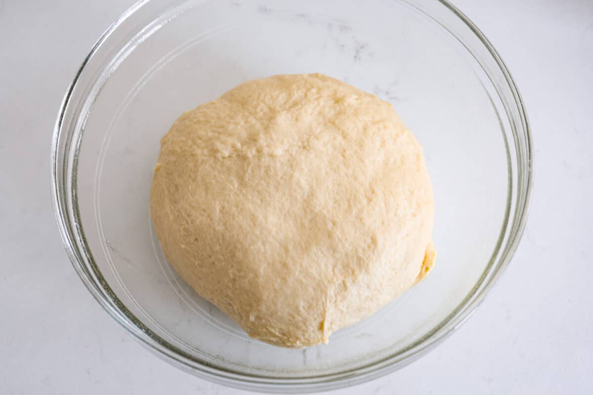 Perfectly soft buttery rolls will be your classic go-to roll recipe! They are tender fluffy, and baked with a buttery golden top. These rolls are sure to be a family favorite! Fifth process photo of the dough rising in a bowl.