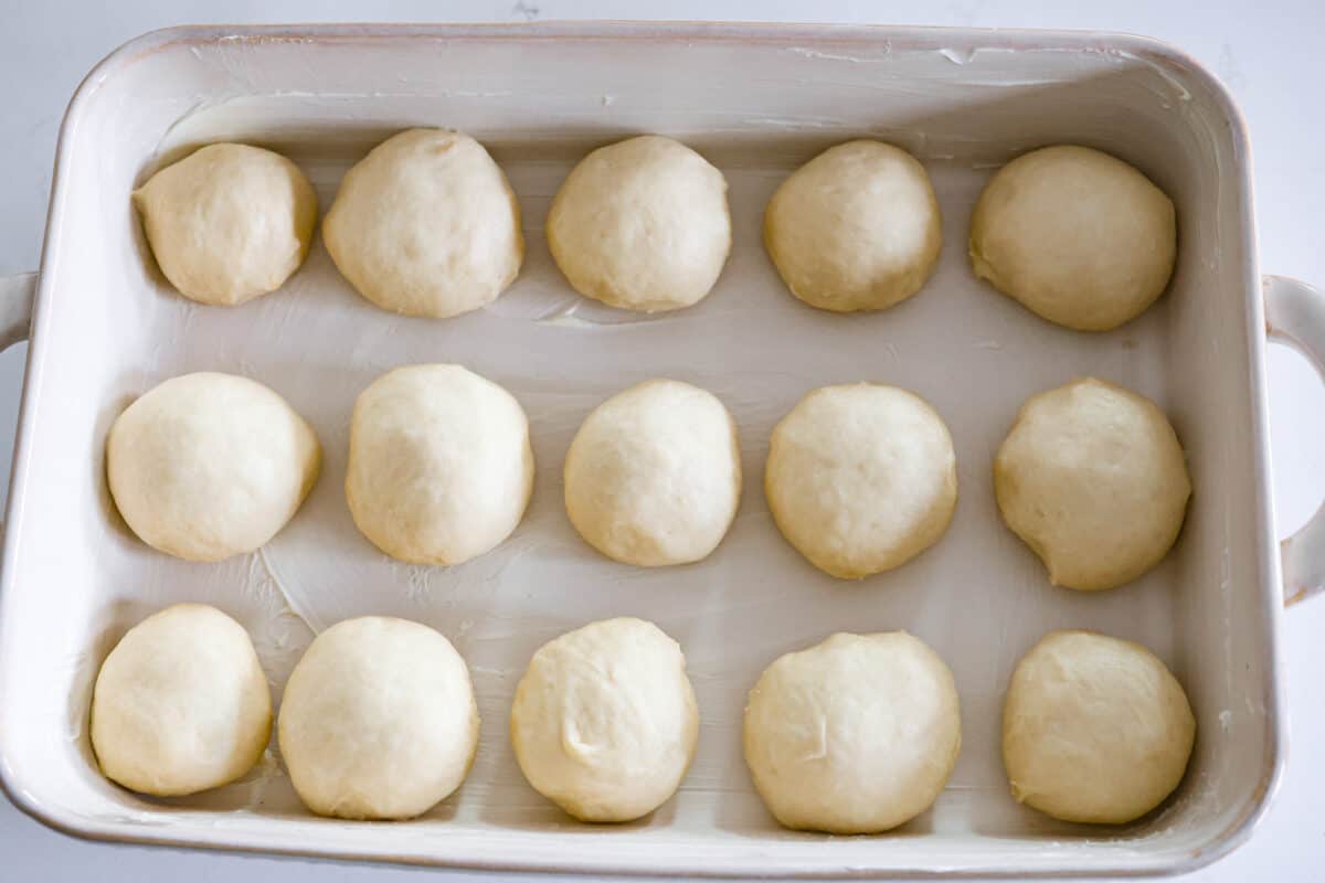Perfectly soft buttery rolls will be your classic go-to roll recipe! They are tender fluffy, and baked with a buttery golden top. These rolls are sure to be a family favorite! Sixth process photo of the dough shaped into rolls and placed in a pan.