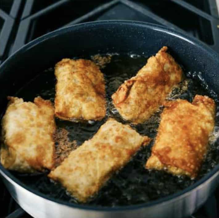 These are the BEST Southwest chicken egg rolls! It's aย colorfulย combination of corn, black beans, fresh veggies, shredded cheese, and chicken. This tasty mixture is flavored in savory southwestย seasonings then fried in a crispy egg roll wrapper. These won't last long at your next party! Sixth photo of the egg rolls browned and fried on all sides.