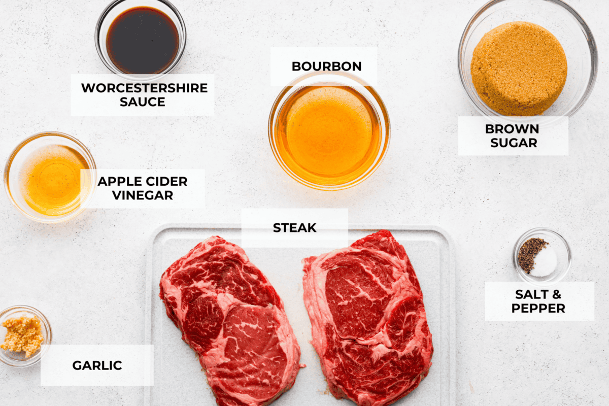 Fire up the grill for these mouthwatering Grilled Bourbon Steaks! Marinated in a blend of whiskey, brown sugar, and savory spices, these steaks are sure to be a hit at your next barbecue. A top view of all of the ingredients individually laid out on a counter and labeled.