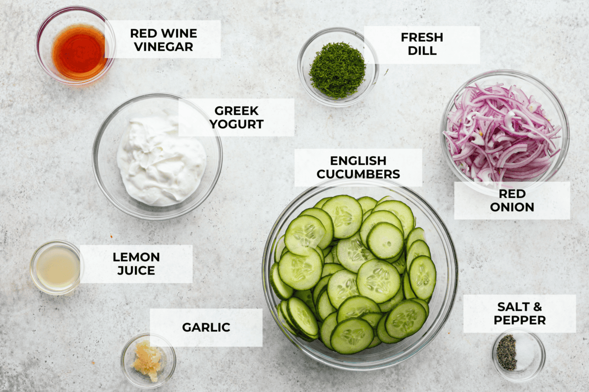Creamy Cucumber Salad is a delicious and refreshing side dish. All it takes is a handful of fresh simple ingredients and 15 minutes. This is the perfect addition to your next summer barbecue! The top view of ingredients in individual glass bowls laid out on a counter and labeled.