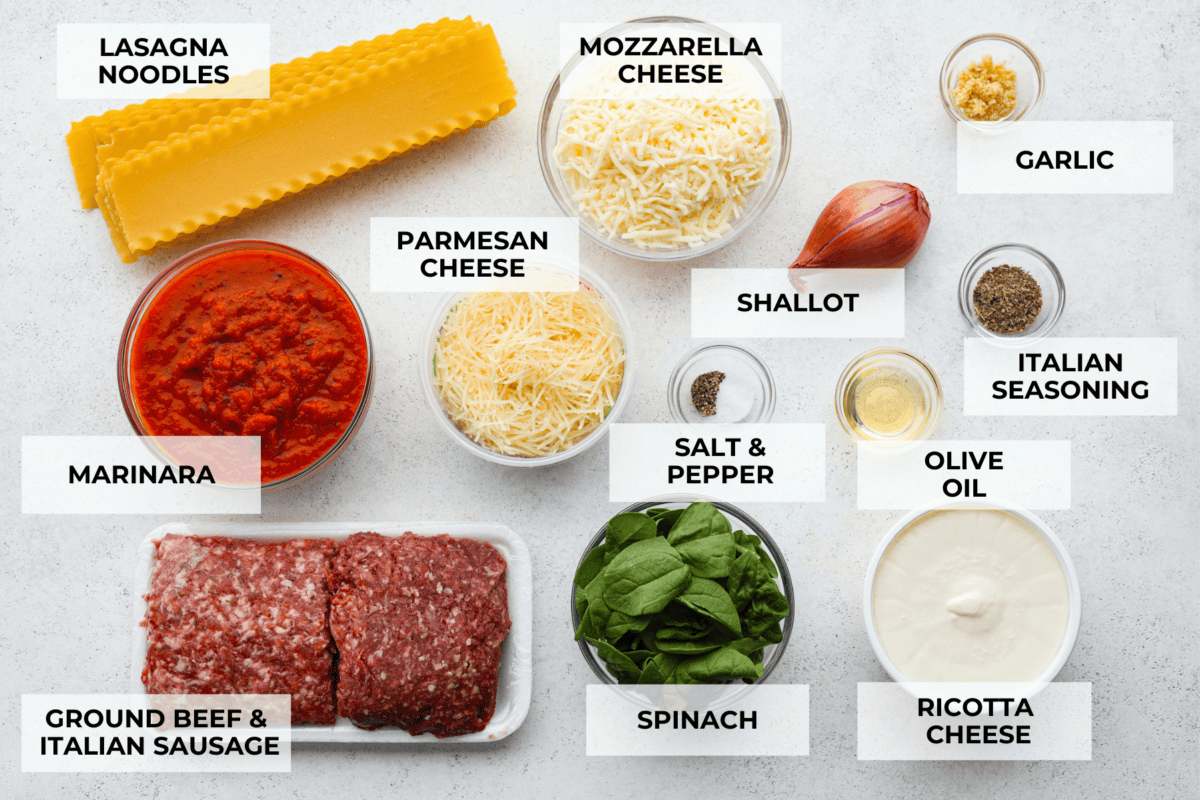 This super easy sheet pan lasagna is stacked with sautรฉedย ground beef and Italianย sausage that are cooked together, marinaraย sauce,ย creamy spinach ricotta, lasagna noodles and melty cheese for an amazingย Italian dinner. A top view of all of the ingredients for sheet pan lasagna in individual bowls, each labeled.
