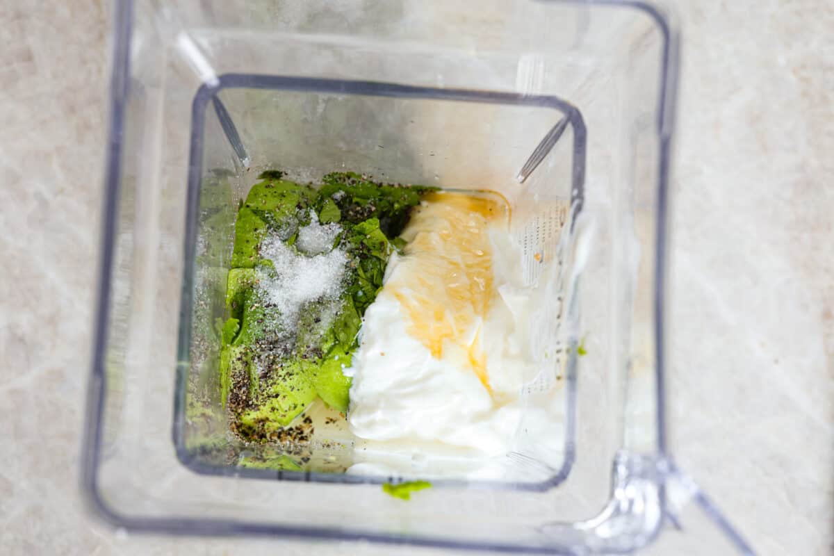 This dressing is packed with flavor and so creamy! It's delicious on salads, burrito bowls, tacos, and even burgers and wraps. I love how quick and easy it is to make with simple ingredients, and it has the perfect balance of tangy, nutty and subtly sweet flavors. Overhead view of blander with ingredients for avocado dressing in it.