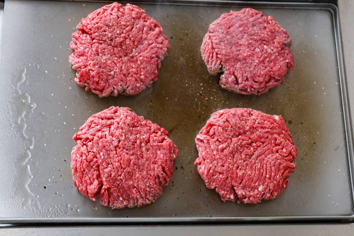 Get ready to be blown away by this Blue Cheese Burger! It's thick, juicy, and filled with flavor. If you love blue cheese dressing, this recipe is for you! That unique tangy flavor is the perfect addition to the juiciest patty ever. Overhead view of 4 raw beef patties on cookie sheet.
