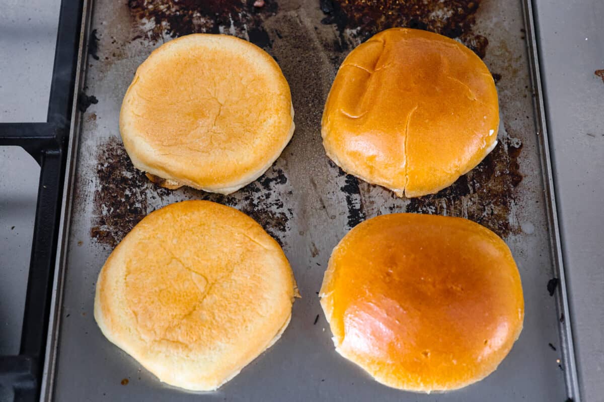 Get ready to be blown away by this Blue Cheese Burger! It's thick, juicy, and filled with flavor. If you love blue cheese dressing, this recipe is for you! That unique tangy flavor is the perfect addition to the juiciest patty ever. Overhead view of hamburger buns on a griddle being toasted.