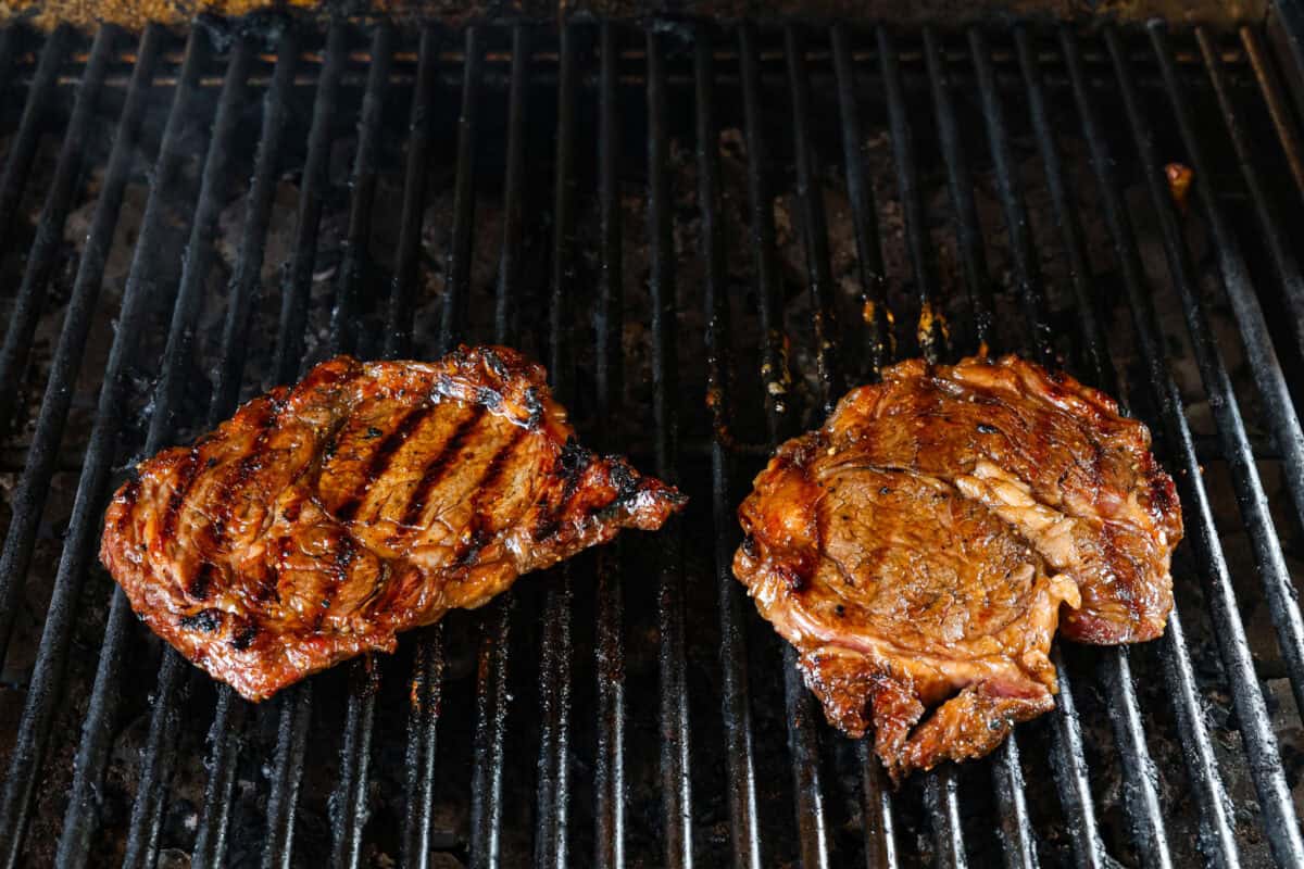 Fire up the grill for these mouthwatering Grilled Bourbon Steaks! Marinated in a blend of whiskey, brown sugar, and savory spices, these steaks are sure to be a hit at your next barbecue. Bourbon steak being cooked on the grill.