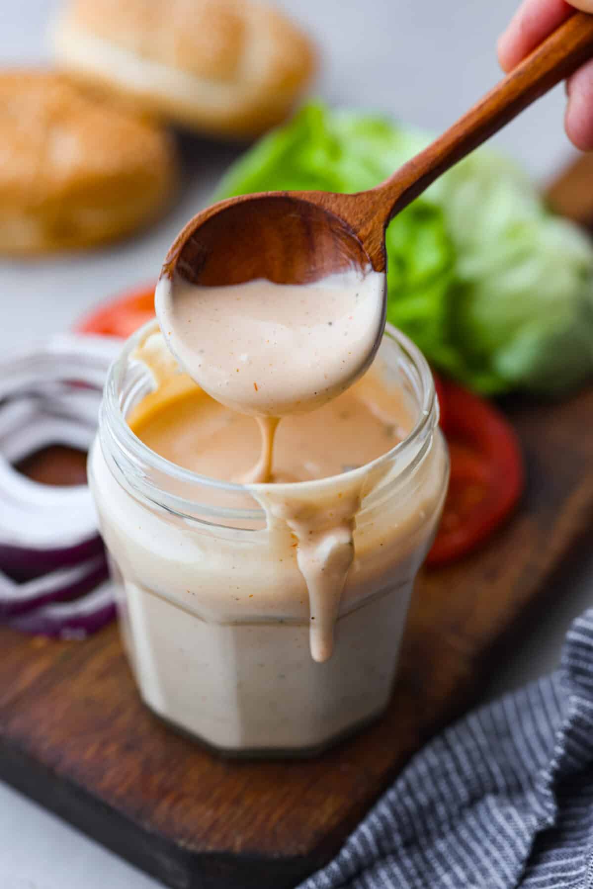This burger sauce is a game-changer for your cookouts, adding a delicious twist to your favorite meals. Whip it up in minutes and enjoy a flavorful blend thatโs perfect for burgers or as a dip for fries. Burger sauce in a jar with a wooden spoon.