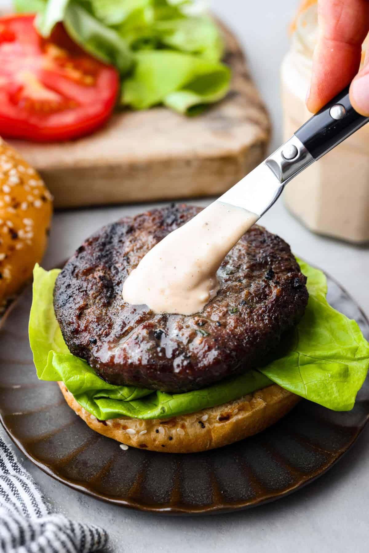 This burger sauce is a game-changer for your cookouts, adding a delicious twist to your favorite meals. Whip it up in minutes and enjoy a flavorful blend thatโs perfect for burgers or as a dip for fries. Burger sauce being spread onto a patty that is on a bun with lettuce.