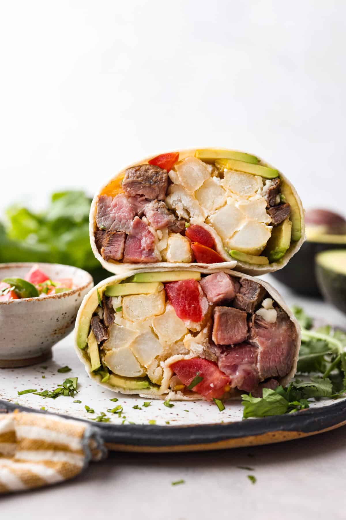 This delicious California Burrito is filled with well-seasoned grilled steak, pepper jack cheese, French fries, pico de Gallo, sour cream and avocado, all wrapped up in a warm flour tortilla. A flavorful lunch or dinner option that will be an absolute hit! A close up of the inside of a California burrito.