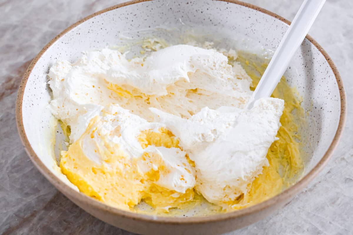 Serve this fun and delicious cookie salad as a dessert or side dish! Everyone will love the sweet fluffy pudding base mixed with mandarin oranges, crushed pineapple, and fudge stripes cookies. Second process photo of cool whip added to the bowl.