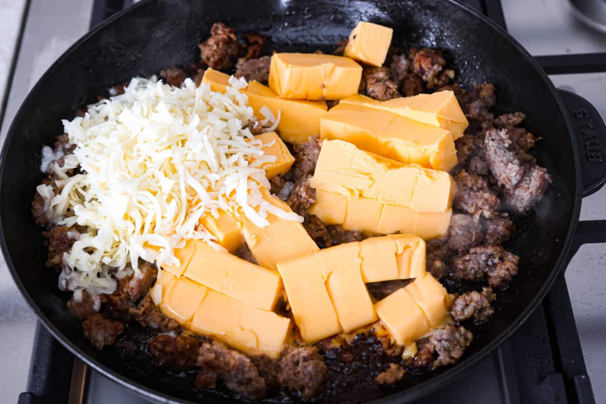 Get ready to rustle up some serious flavor with this Cowboy Queso! Packed with zesty sausage, hearty beans, and a kick of beer, it's the perfect dip for any gathering—just grab your tortilla chips and dig in! Velveeta and Colby jack cheese being added to the sausage.
