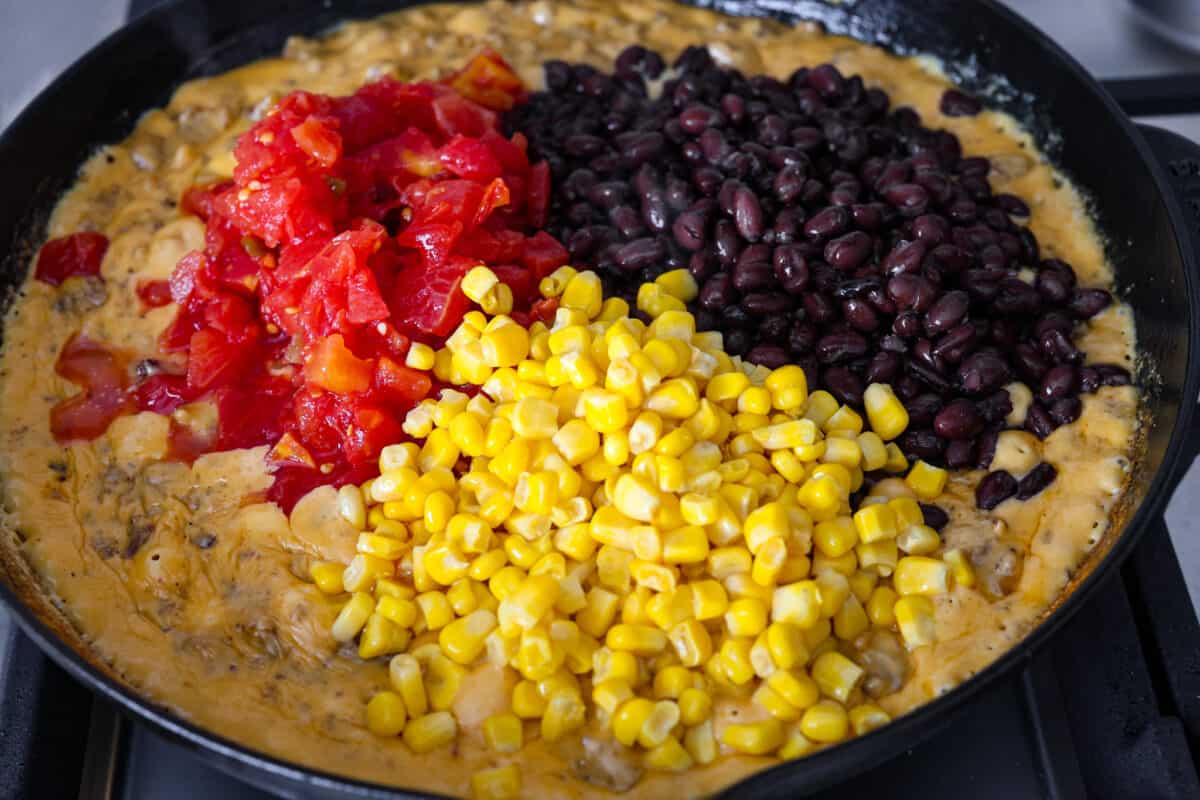 Get ready to rustle up some serious flavor with this Cowboy Queso! Packed with zesty sausage, hearty beans, and a kick of beer, it's the perfect dip for any gathering—just grab your tortilla chips and dig in! Veggies being added to the cowboy quest in the skillet.