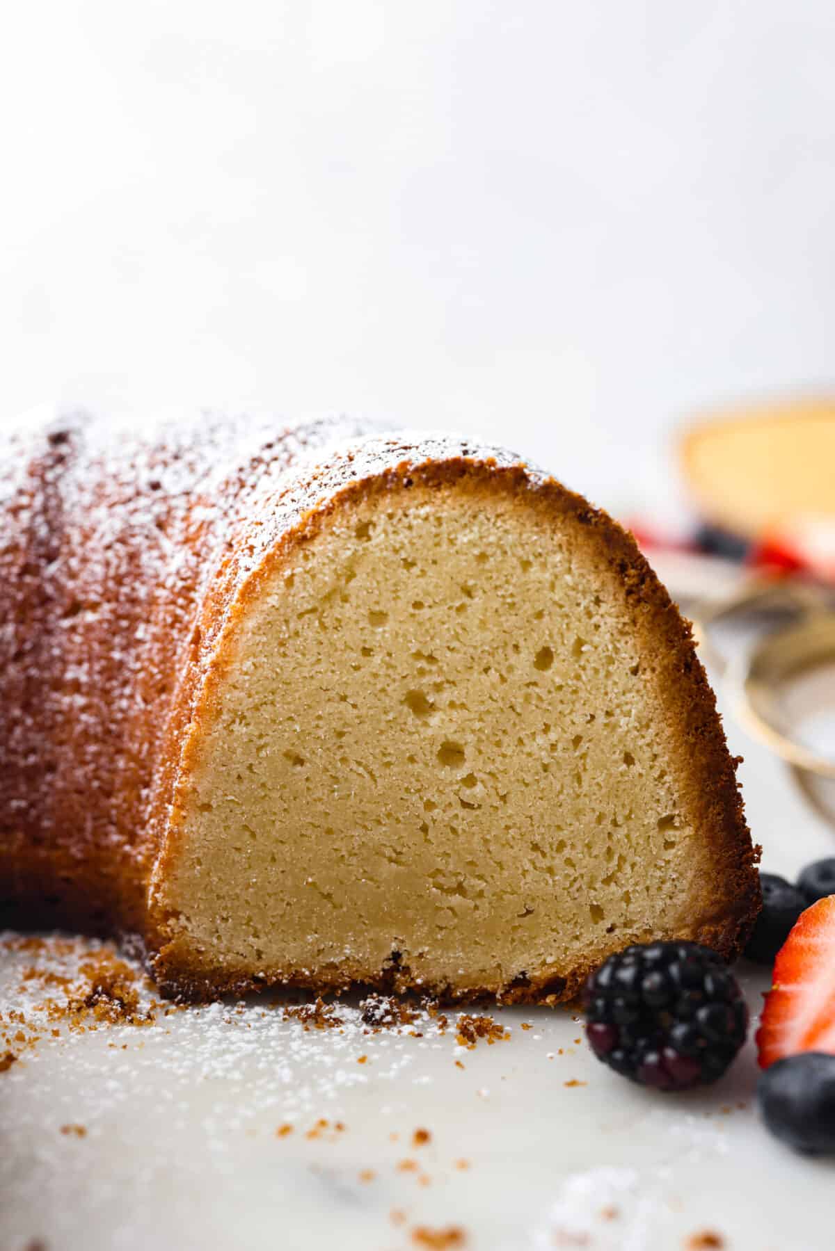 This Cream Cheese Pound Cake is a tender, moist, and flavorful dessert that's a new spin on traditional pound cake. Plus, it’s super simple to make! Top it off with whipped cream and fresh berries or enjoy plain! A bundt cake with a slice cut out of it so you can see the inside.