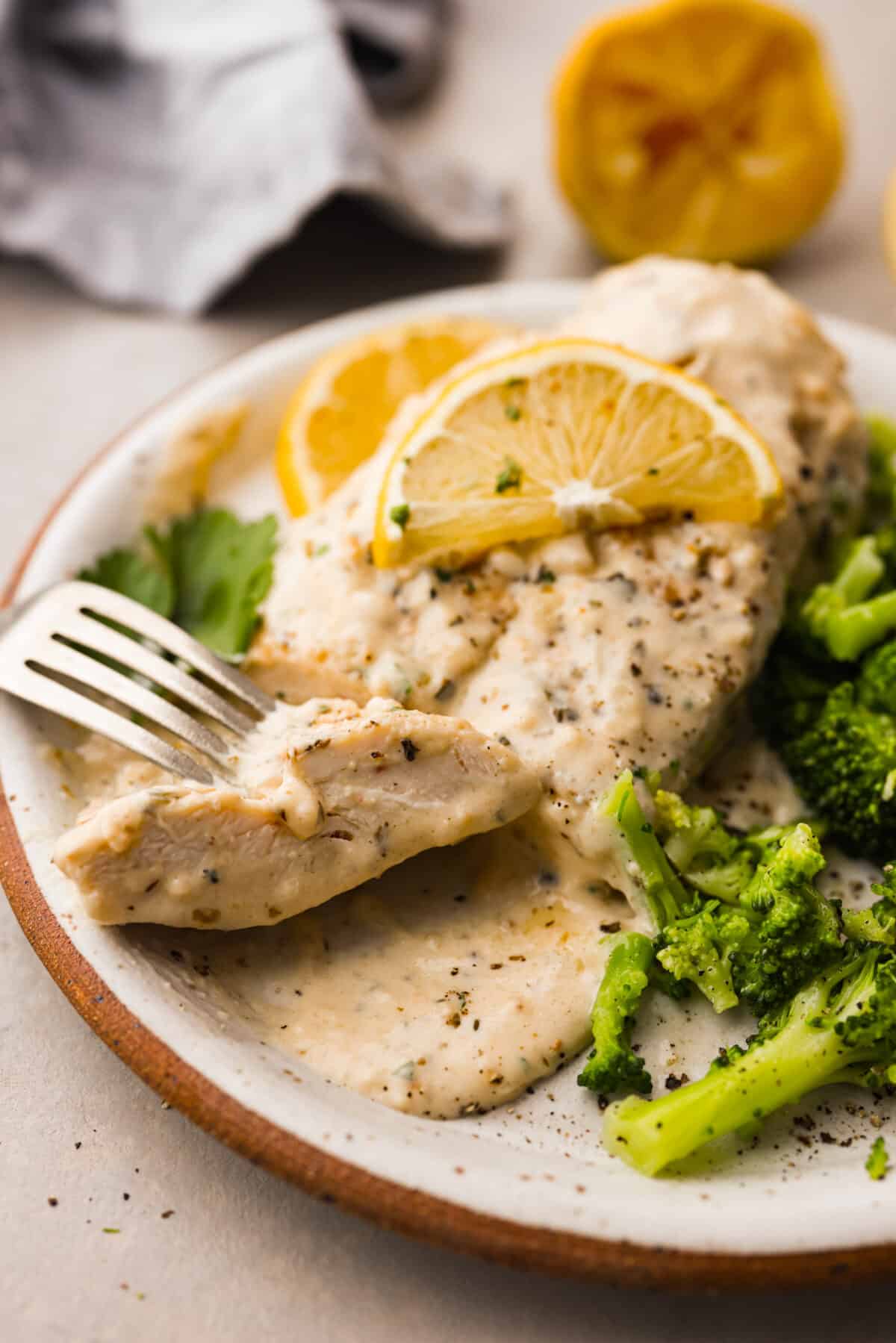 Creamy Lemon Parmesan Chicken is an incredible restaurant-quality meal you can make in under 30 minutes. Tender, juicy chicken is smothered in a creamy lemon parmesan sauce- itโs a meal the family will go crazy for!ย A serving of the recipe on a stoneware plate.