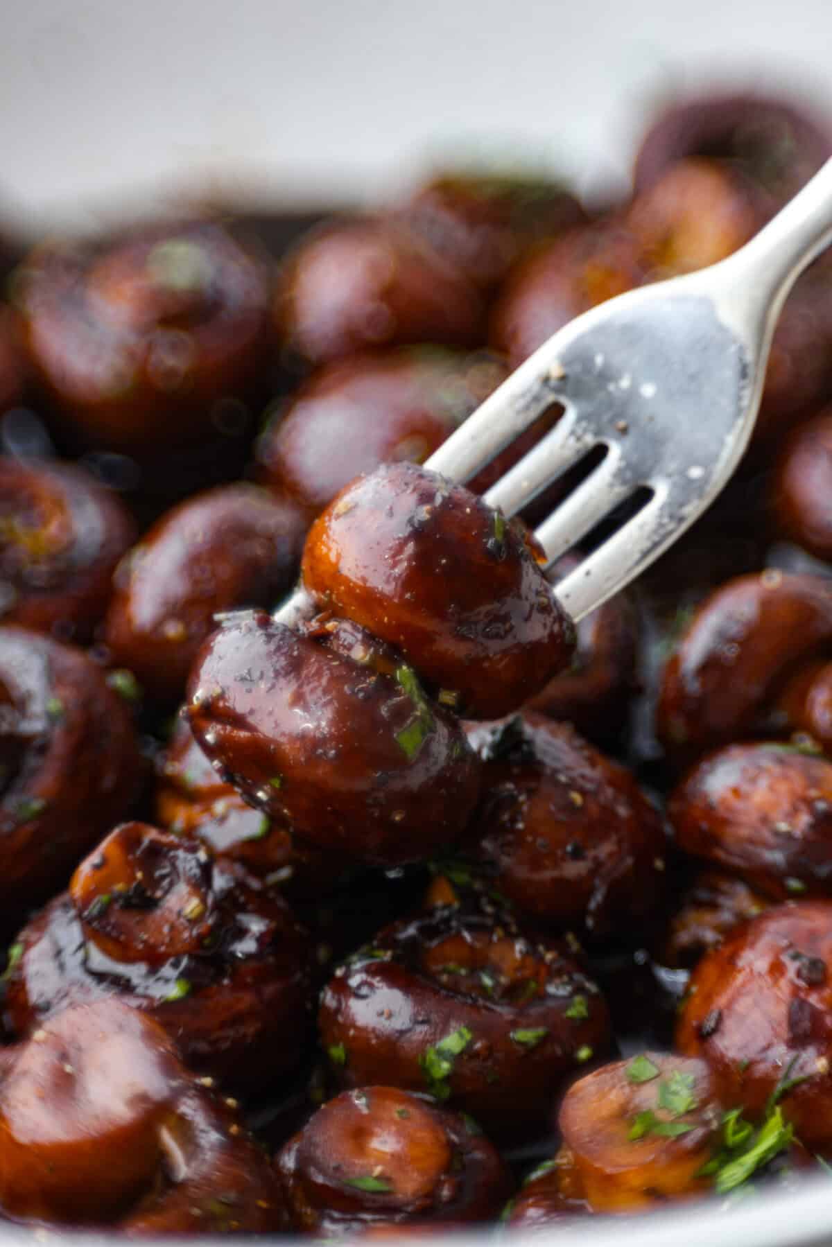 The depth of flavors in these garlic balsamic mushrooms is next level! Sauteed mushrooms are coated in a sweet balsamic sauce loaded with herbs. It's a simple and impressive side dish that only takes minutes to prepare Close view of a fork poking mushrooms from the skillet.