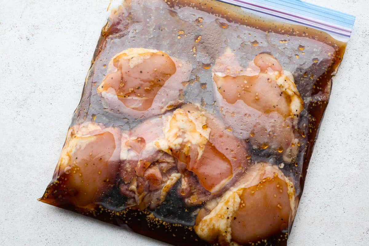 One bite of this grilled bourbon chicken and your tastebuds will be dancing with delight! It's marinated in a flavorful homemade bourbon sauce that tastes amazing. You will be making it on the regular once you see what a huge hit it is! Chicken being marinated in a ziplock bag.