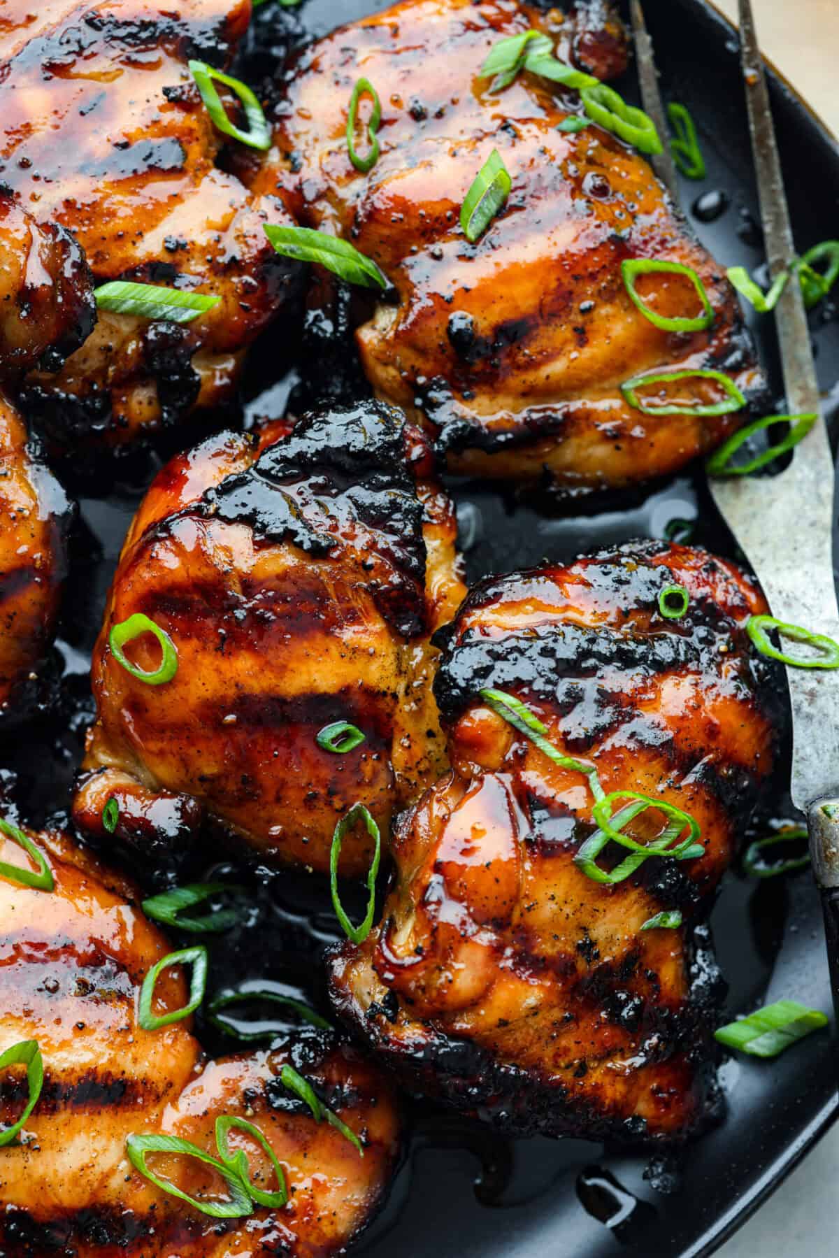 One bite of this grilled bourbon chicken and your tastebuds will be dancing with delight! It's marinated in a flavorful homemade bourbon sauce that tastes amazing. You will be making it on the regular once you see what a huge hit it is! A close up of grilled chicken thighs marinated in bourbon.
