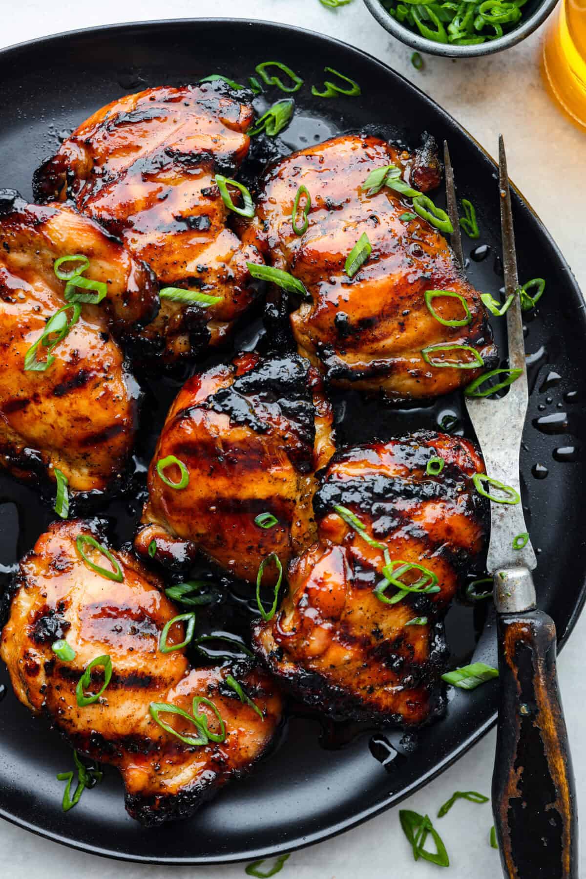 One bite of this grilled bourbon chicken and your tastebuds will be dancing with delight! It's marinated in a flavorful homemade bourbon sauce that tastes amazing. You will be making it on the regular once you see what a huge hit it is! Grilled bourbon chicken on a black plate.