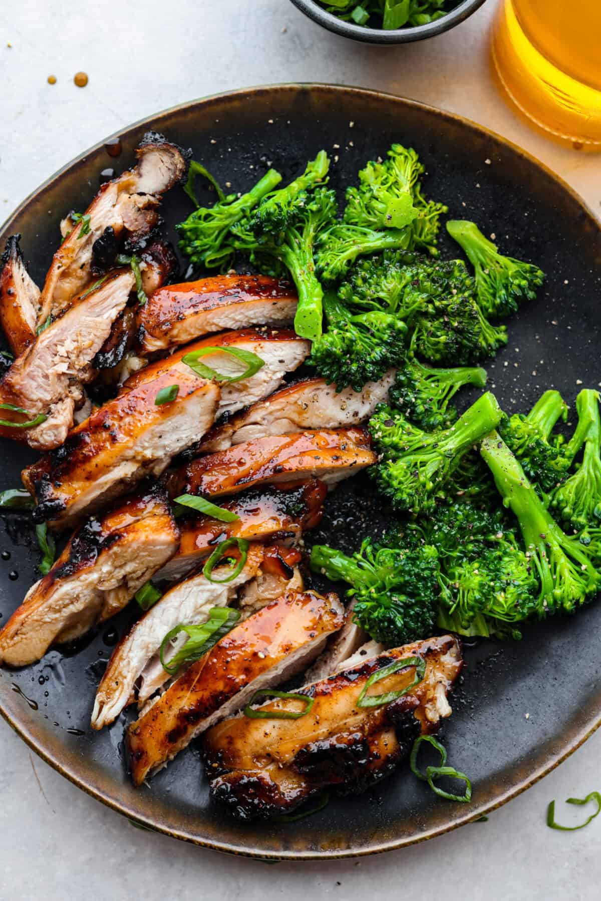 One bite of this grilled bourbon chicken and your tastebuds will be dancing with delight! It's marinated in a flavorful homemade bourbon sauce that tastes amazing. You will be making it on the regular once you see what a huge hit it is! A plate with sliced chicken and broccoli florets.