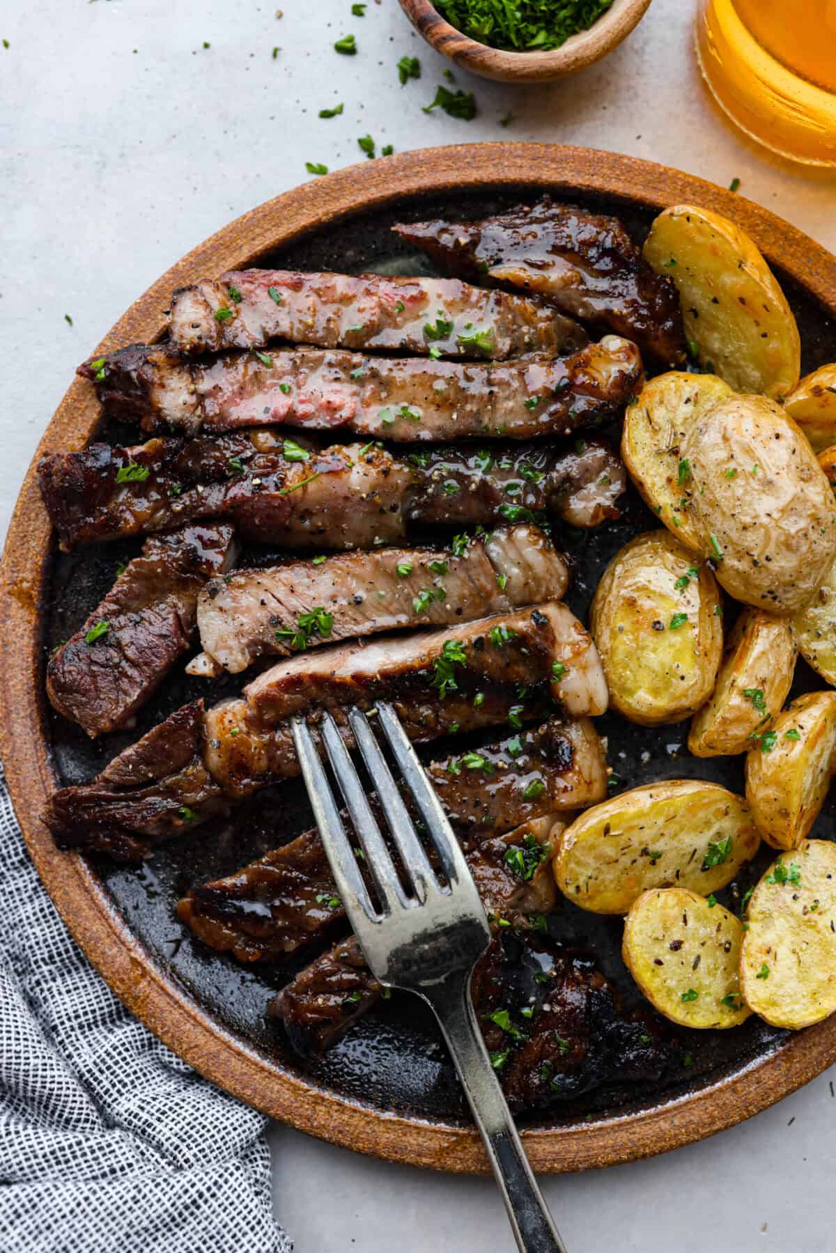 Fire up the grill for these mouthwatering Grilled Bourbon Steaks! Marinated in a blend of whiskey, brown sugar, and savory spices, these steaks are sure to be a hit at your next barbecue. Steak and potatoes on a plate, ready to eat.