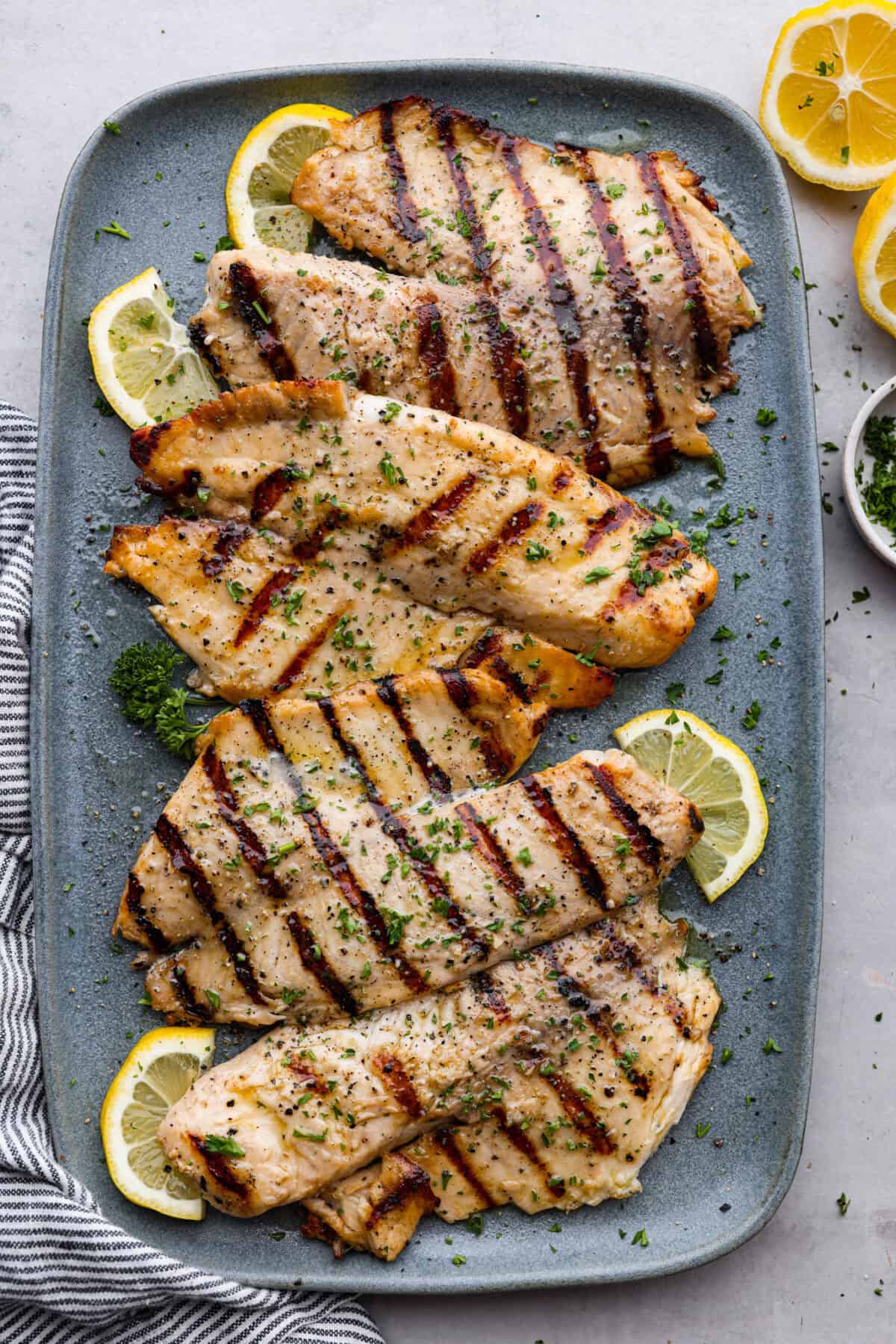 Fire up the grill! This grilled tilapia is deliciously seasoned and has the best flaky texture. Top view of grilled tilapia on a platter.