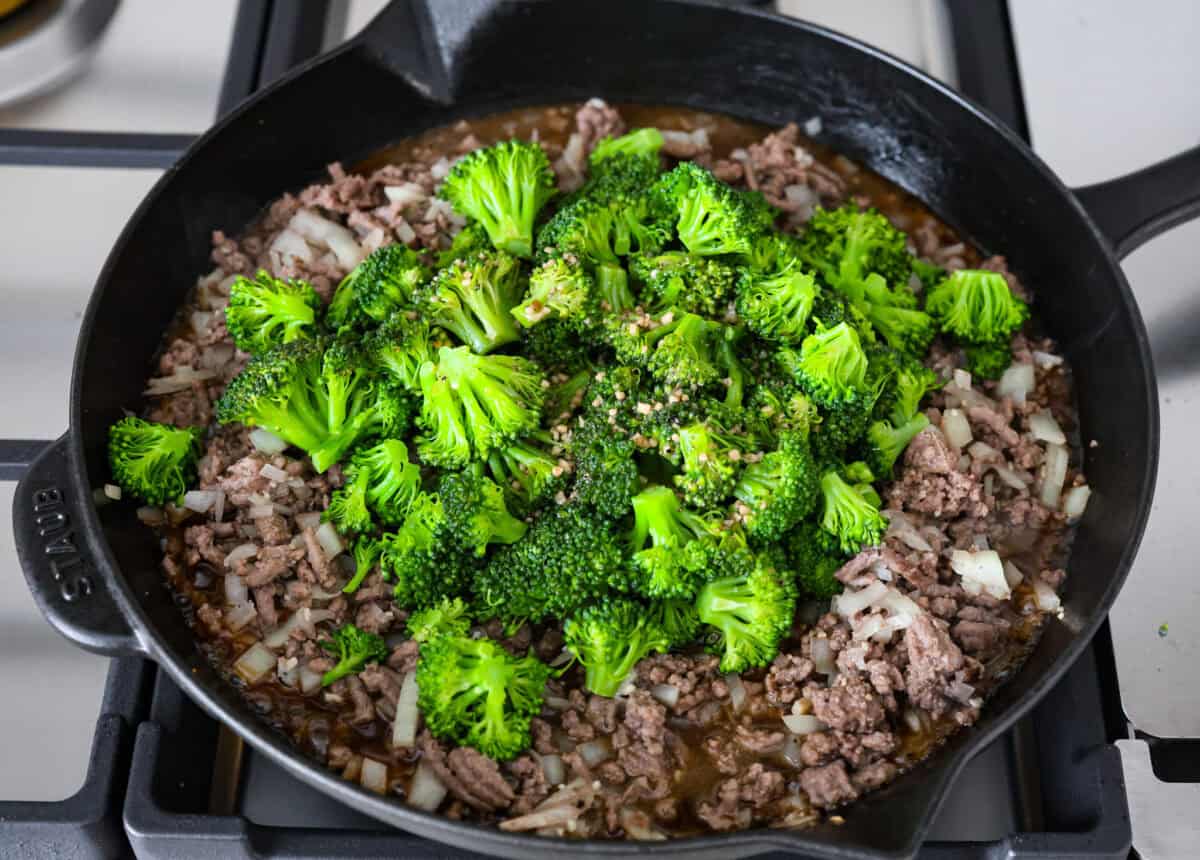 Get ready to enjoy a delicious and easy ground beef and broccoli stir-fry thatโs perfect for a quick weeknight dinner. This flavorful dish combines tender broccoli, savory beef, and a rich, tangy sauce, all served over steamed rice for a satisfying meal the whole family will love. Overhead shot of a skillet with beef, onions and broccoli with sauce.
