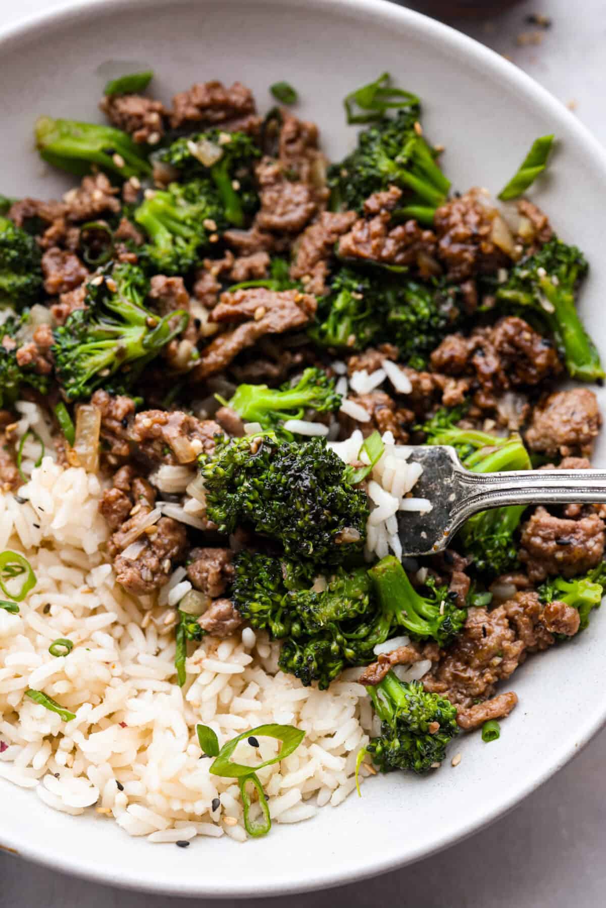 Get ready to enjoy a delicious and easy ground beef and broccoli stir-fry thatโs perfect for a quick weeknight dinner. This flavorful dish combines tender broccoli, savory beef, and a rich, tangy sauce, all served over steamed rice for a satisfying meal the whole family will love. Close up shot of plated ground beef and broccoli over rice with a bite on a fork.