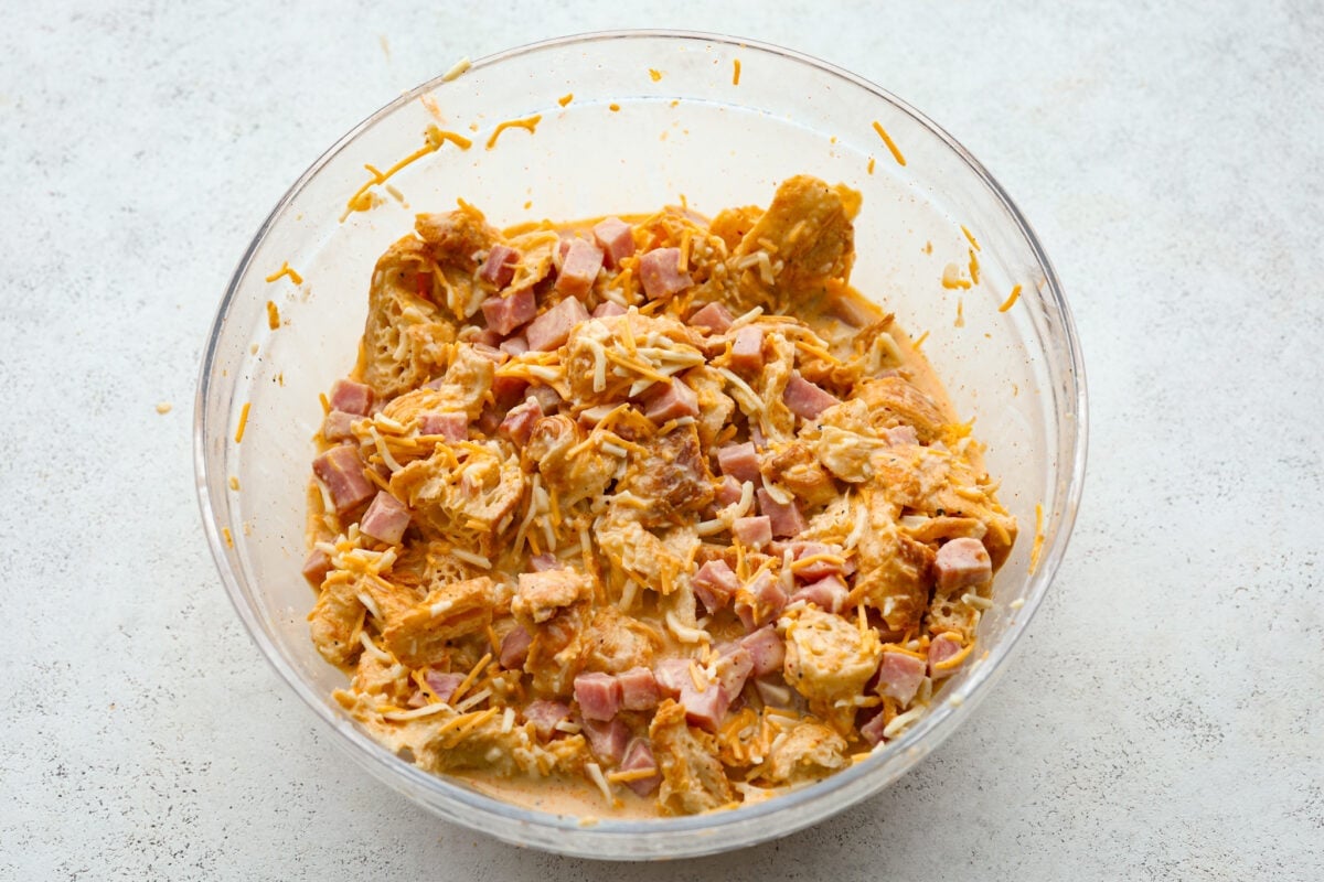 This Ham and Cheese Croissant Casserole is filled with comforting flavors of croissants, eggs, ham and plenty of melty cheese. It's quick and easy to throw together for a yummy dish that works for breakfast, lunch or dinner! The egg mixture combined with the croissants, cheese and ham.