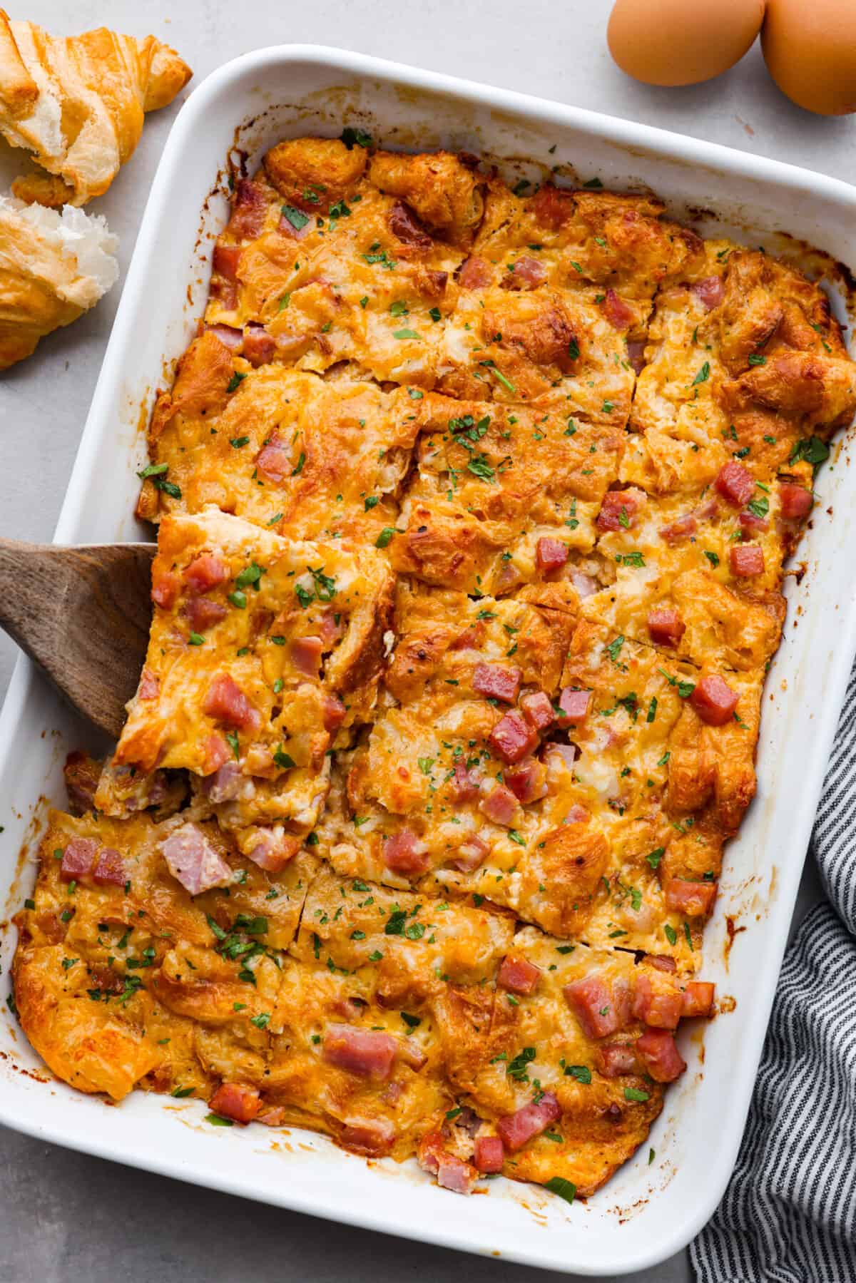 This Ham and Cheese Croissant Casserole is filled with comforting flavors of croissants, eggs, ham and plenty of melty cheese. It's quick and easy to throw together for a yummy dish that works for breakfast, lunch or dinner! The top view of a ham and cheese croissant casserole.