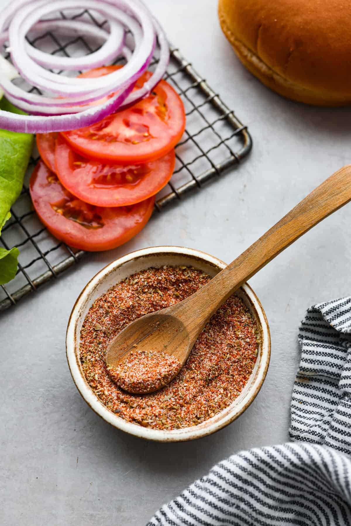 This flavorful Burger Seasoning will take your favorite burger recipe to a new level of delicious! It’s a simple, yet tasty blend of staple spices and seasonings that makes each bite better than the next! Burger seasoning in a small bowl with a wood spoon.