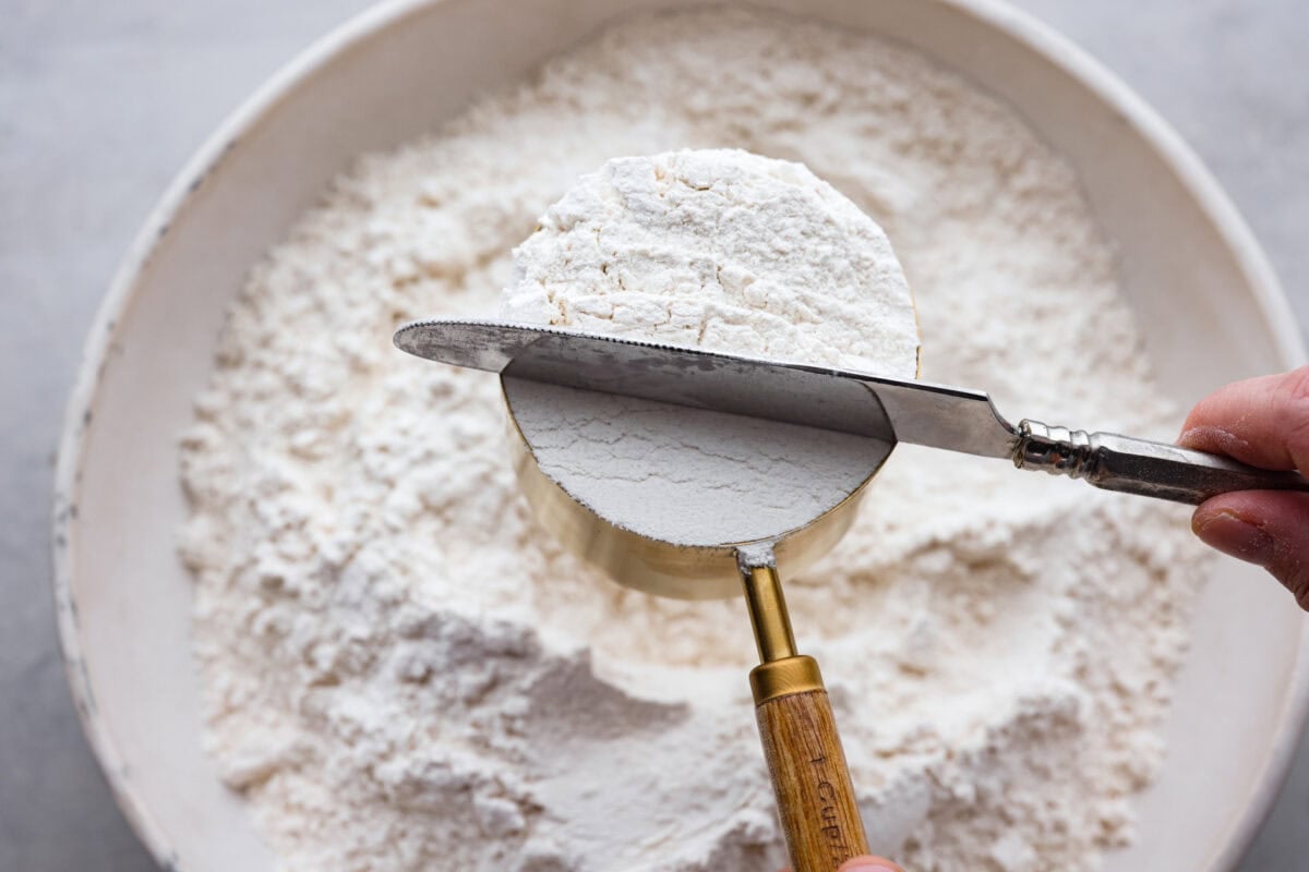 Whether you are a seasoned baker or just starting out, this informational post has all of my tips and tricks on how to properly measure baking ingredients. A picture of a knife sweeping off excess flour to show how to properly measure baking ingredients.