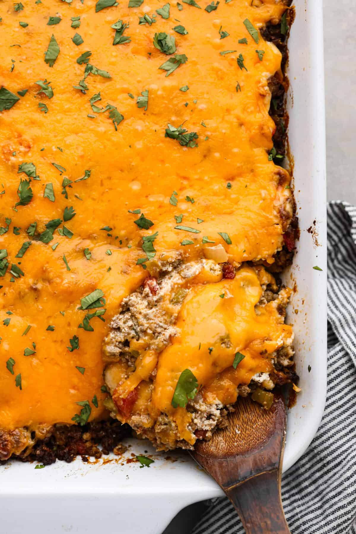 This delicious John Wayne Casserole is Mexican comfort food at its finest! Layers of seasoned ground beef, creamy cheddar cheese mixture, and more shredded cheese are baked on top of a biscuit crust for a crowd-pleasing family dinner! The top view of John Wayne Casserole in a baking dish.
