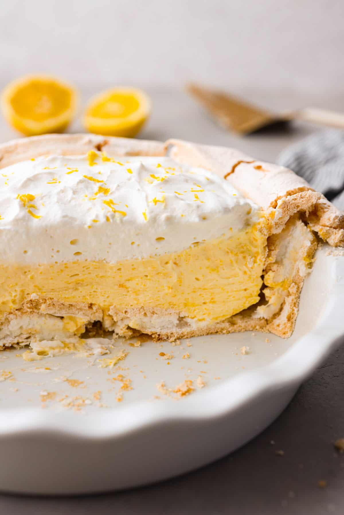 Lemon angel pie is a delightful dessert straight from heaven! It has a creamy lemon filling inside a sweet, airy meringue crust, then topped with fresh whipped cream. Every bite is pure bliss! Close view of the sliced lemon angel pie in the pie dish.